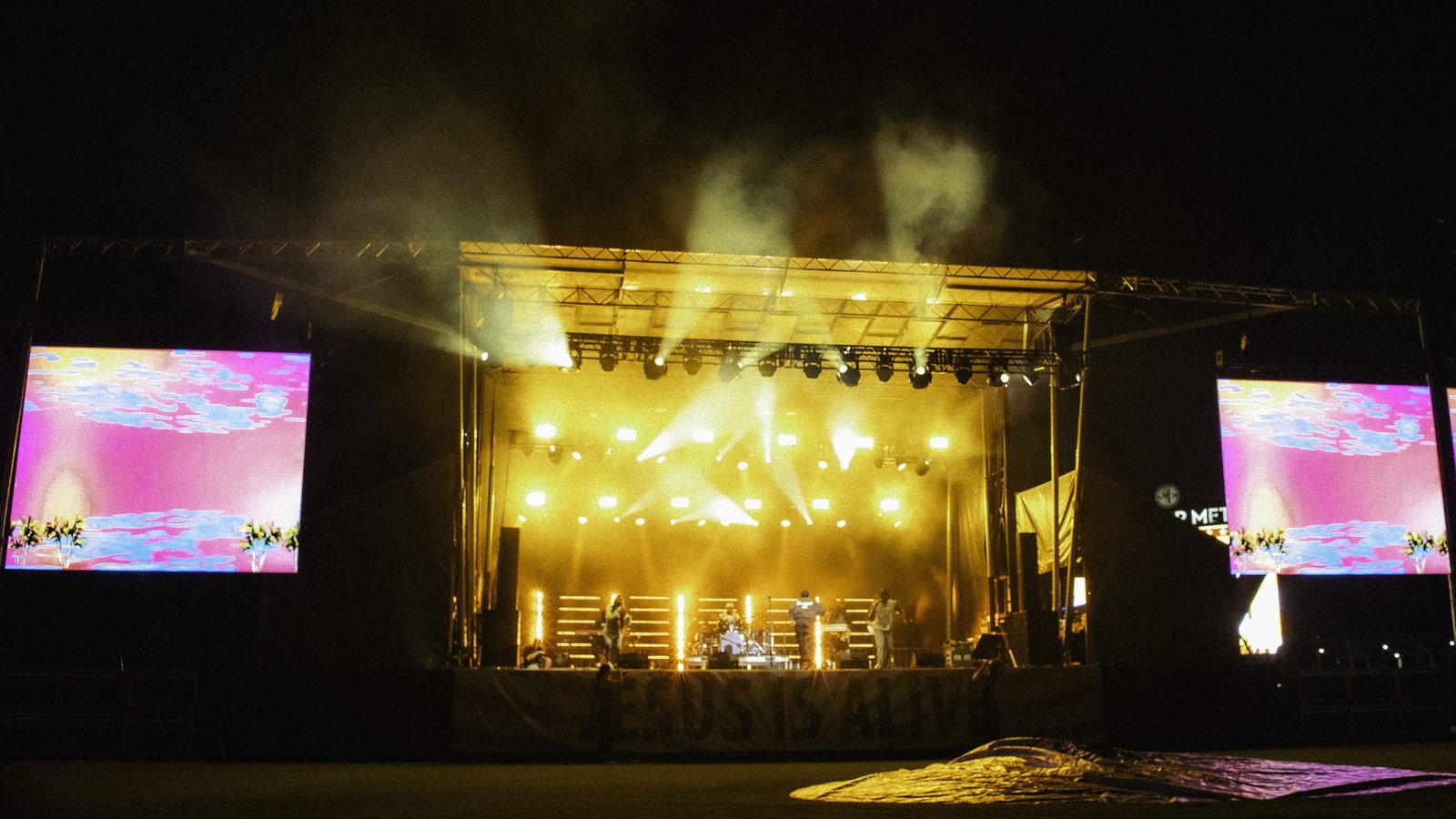 Concert stage at night with warm light beams and LED screens